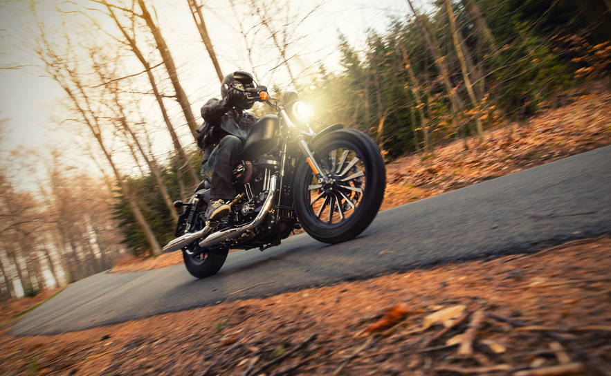 Young man riding chopper on road in forest